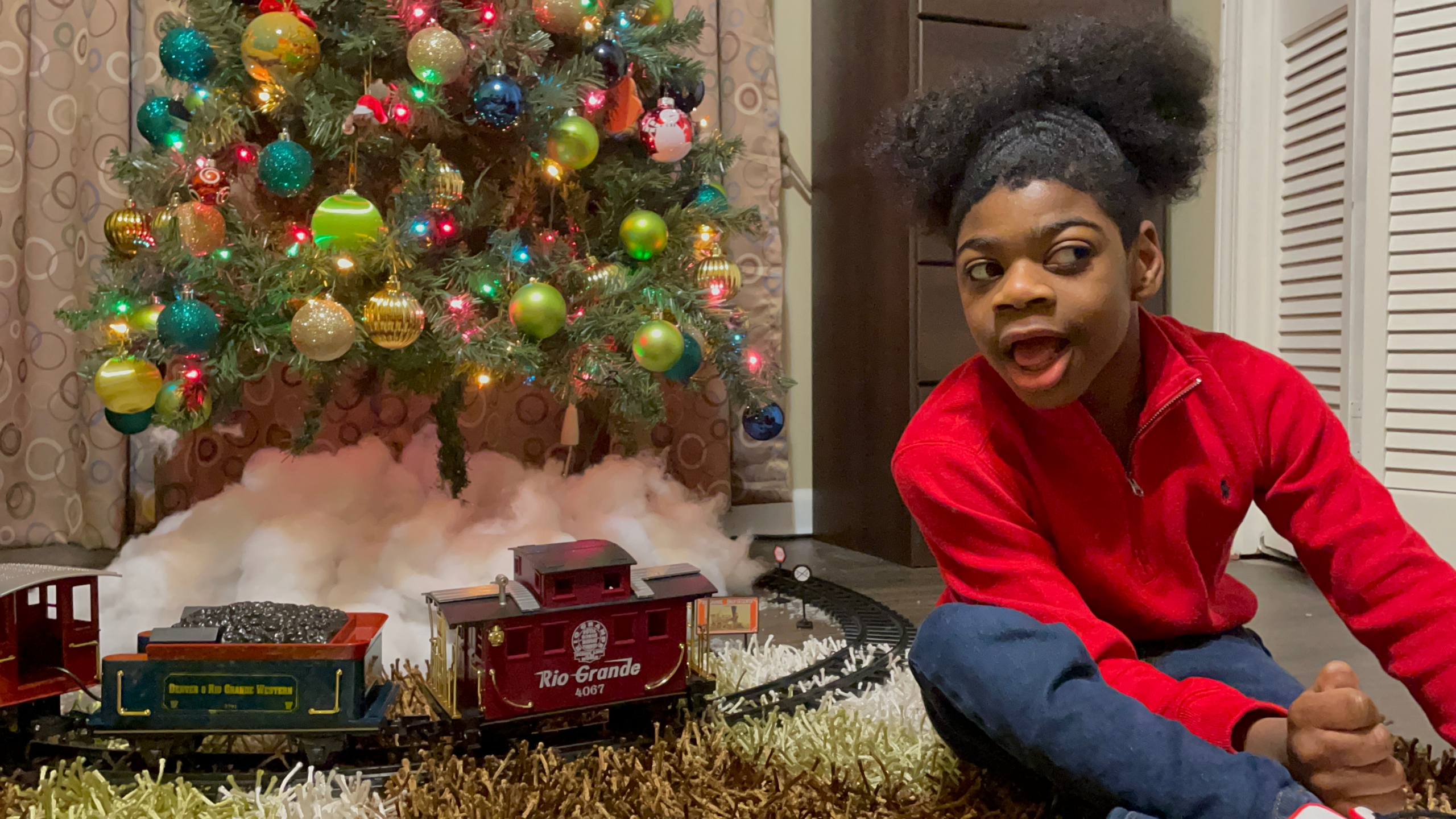 Young boy sitting in front of a Christmas tree.