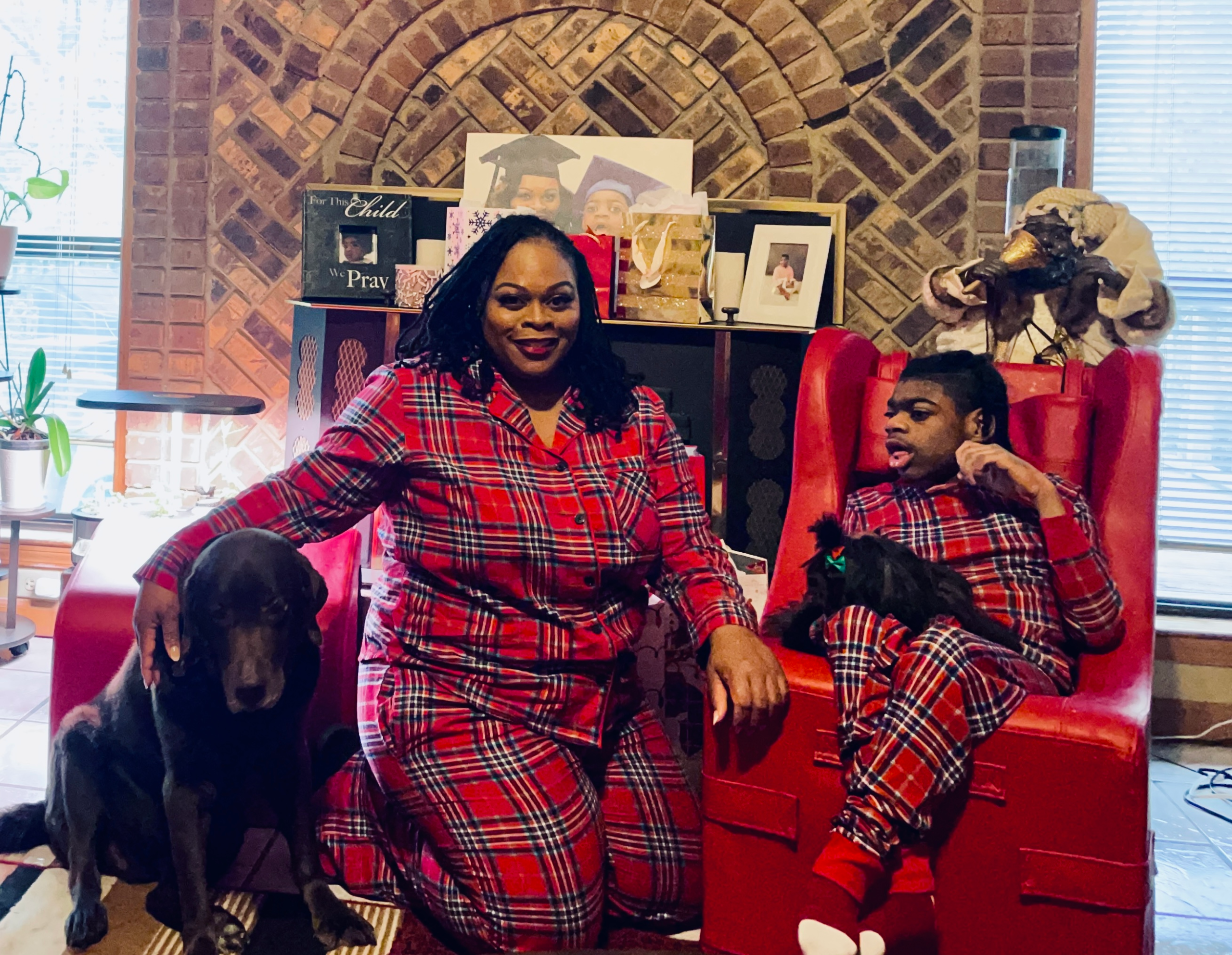Family in matching Christmas pajamas with mother, son, and two pups